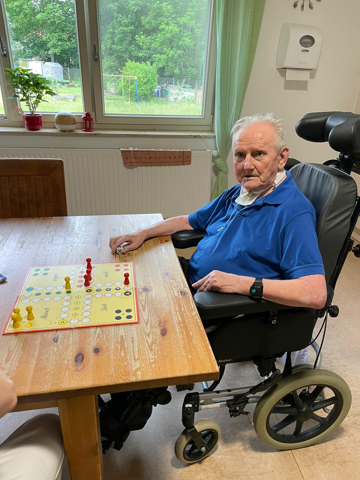 Mensch ärgere dich nicht Älterer Mann im Rollstuhl beim Gesellschaftsspiel ‚Mensch ärgere dich nicht‘.